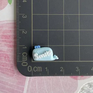 Mini blue whale resin charm with white smile letters for DIY hair clips and craft accessories.
