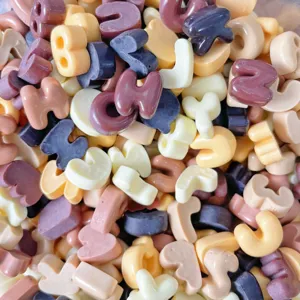 Mini resin alphabet letter charms in assorted neutral colors for DIY crafts and phone cases.