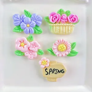 Close-up detail of colorful floral resin flatback charms including flowers, basket, and sign.