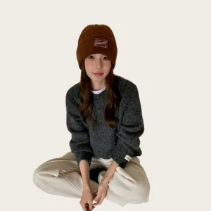 Detailed shot of a cozy brown knitted beanie and dark grey sweater winter outfit style.