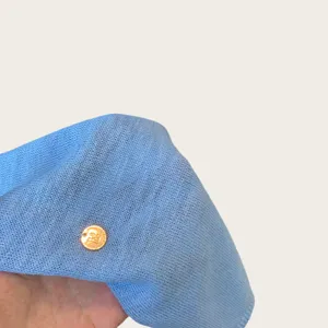 Close up of light blue knit shawl fabric texture and cute golden coin charm detail.