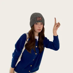 Close-up detail of the cozy gray knitted beanie hat with custom woven patch, winter style.