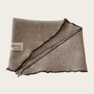 Detailaufnahme eines Wollmischgewebe-Strickdreischeitertuchs mit kontrastierender dunkler Kante.