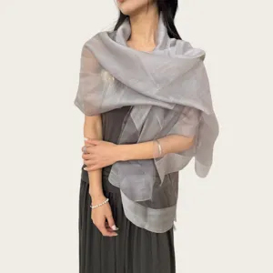 Vista detallada de una bufanda gris ligera y transparente drapeada con elegancia, tejido suave.
