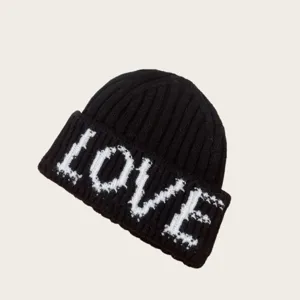 Gros plan détaillé du bonnet tricoté noir d'hiver avec motif de lettres LOVE blanches tricotées.
