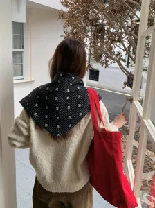 Detalle del pañuelo triangular de punto de invierno con diseño floral cálido y acogedor.
