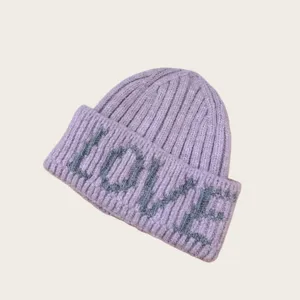 Gros plan sur un bonnet en tricot lavande avec un motif de lettres LOVE grises sur le bord.