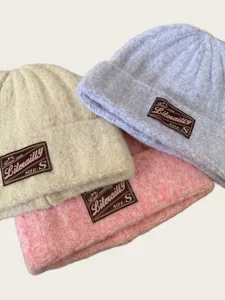 Close-up detail of cozy knit beanie hat with woven brand tag, soft winter thermal texture.