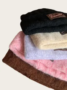 Close-up detail of stacked winter knitted beanie caps in assorted colors showing soft texture.