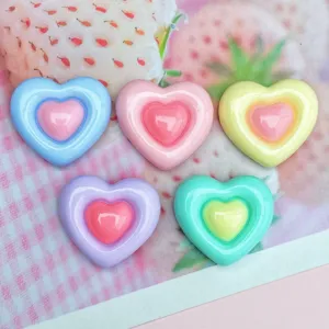 Primo piano di ciondoli in resina a cuore bicolore colorati, accessori fai da te lucidi.