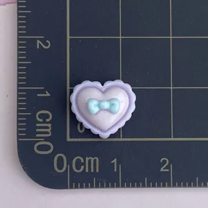Mini resin heart charm with bow detail, perfect for DIY nail art and craft decoration projects.