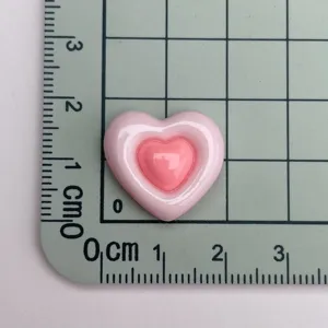 Primo piano dettaglio di patch cabochon in resina cuore rosa lucido bicolore.