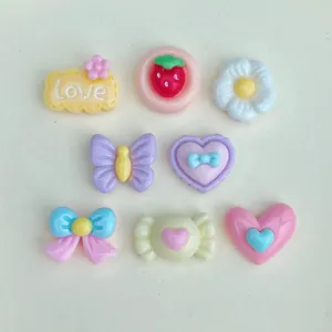 Close up of cute resin cabochons, sweet candy and bow charms for DIY nail art and crafts.
