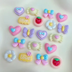 Close-up detail of assorted cute resin cabochons, hearts, bows, and craft charms for DIY nail art.