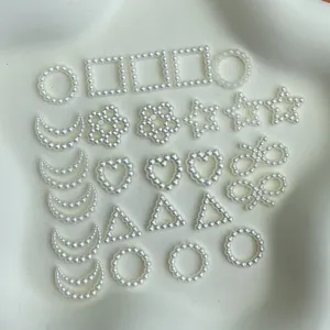 Closeup of assorted white pearl DIY charms in geometric and cute shapes for handmade crafts.