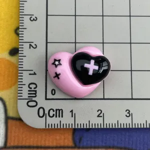 Vue de détail rapprochée du pendentif cœur en résine rose et noir avec croix pour coques.