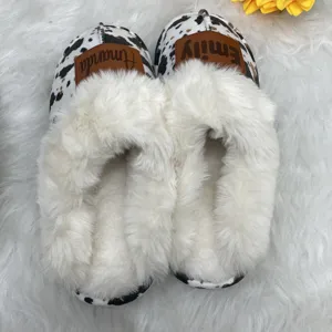 Close-up of personalized cow print slippers with fluffy white faux fur and name patches