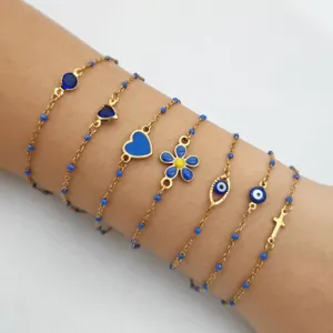 Detailed shot of multi-layer gold chain bracelets with blue enamel evil eye hearts and cross.