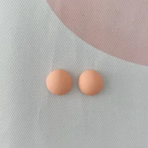 Primo piano di minuscoli cabochon in resina opaca color pesca, ideali per nail art e fai-da-te.