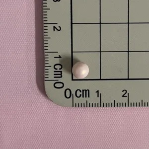 Λεπτομερής λήψη ροζ πέρλας χάντρας DIY αξεσουάρ σε γκρι χαλάκι μέτρησης με πλέγμα.