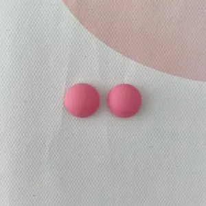 Primo piano di mini cabochon rotondi in resina rosa, perfetti per nail art fai da te e custodie.