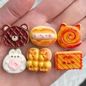 Primer plano de cabujones de resina, dijes surtidos de pan y animales para manualidades.
