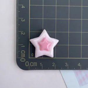 Gros plan détaillé d'un charm étoile en résine rose sur un tapis de coupe gradué.