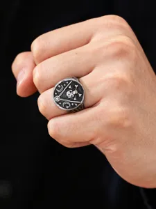 Close-up of a vintage stainless steel skull and star moon ring for men on finger.