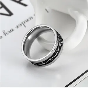 Close-up of men's stainless steel ring with black dragon pattern engraving on band.
