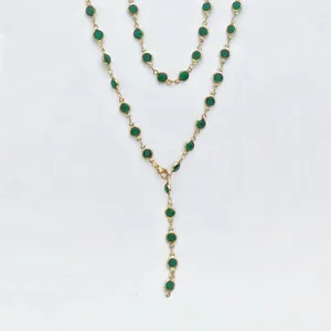 Close up detail view of the gold tone chain necklace with green bezel set round stones.