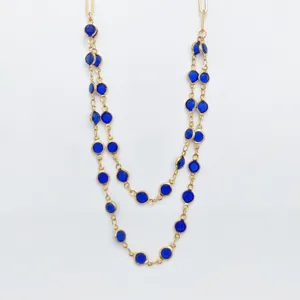 Double layer gold tone stainless steel station necklace with vibrant blue bezel set crystals.