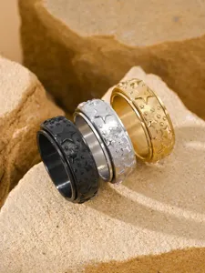 Detailed macro view of three textured rotatable star rings in black, gold, and silver colors