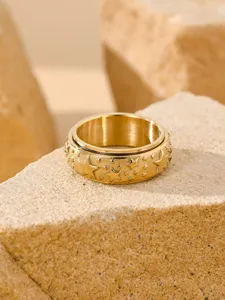 Macro view of a gold spinner ring featuring embossed star patterns on textured stone.