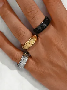 Close-up of three retro star spinner rings in black, gold, and silver on a hand