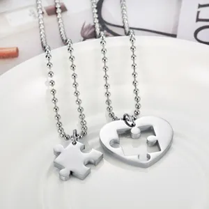Detailed view of heart and puzzle piece couple necklaces in polished stainless steel
