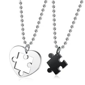 Close-up detail of interlocking stainless steel heart and puzzle piece couple necklaces