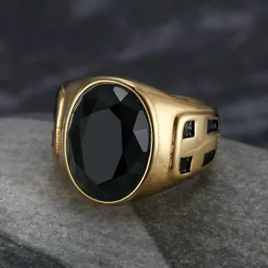 Nahaufnahme eines goldenen Herrenrings mit schwarzem Stein und Kreuz-Totem-Motiv
