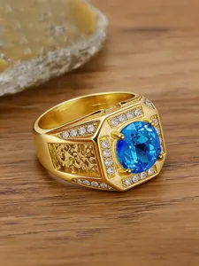 Close-up detail of luxury gold men's ring with blue zircon and vintage dragon engraving