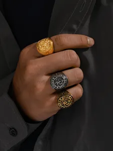 Close-up of three retro military eagle signet rings in gold, silver, and black finishes.