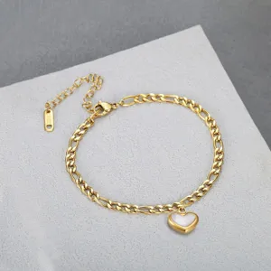 Detailed macro view of a gold-toned heart pendant on a Cuban link chain anklet.