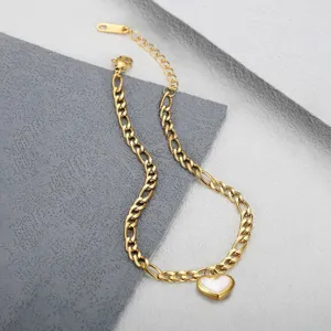 Detail of a gold stainless steel cuban link anklet with a white heart charm