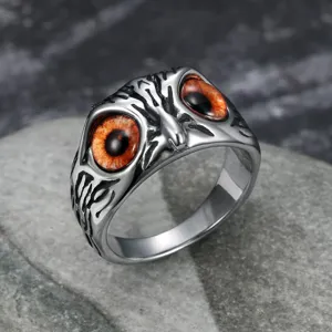 Close-up of vintage stainless steel owl ring with realistic orange eyes in punk style
