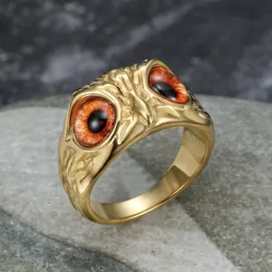 Detailed macro view of gold owl eye stainless steel ring with realistic orange pupils