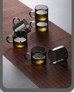 Detailed macro view of smoky grey heat-resistant glass tea cups placed on a bamboo mat.