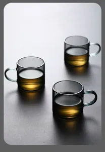Macro view of three heat-resistant smoky gray glass tea cups with golden tea inside