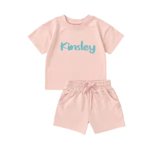 Detailweergave van roze biologisch katoenen kinderset met de naam Kinsley op de top