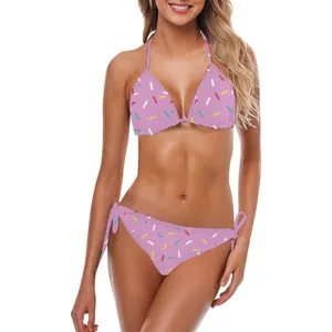 Primo piano di un bikini rosa con stampa a coriandoli colorati e lacci laterali regolabili.