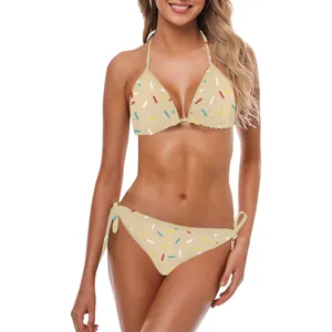 Vista completa di un bikini color crema con stampa sprinkles, top a fascia e laccetti