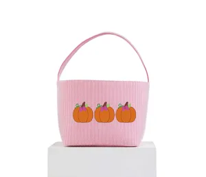 Vista frontale del cesto di Halloween in tela a righe rosa con tre graziose zucche