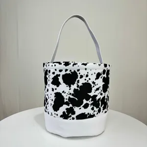 Durable canvas bucket bag featuring classic black and white cow print and a white base